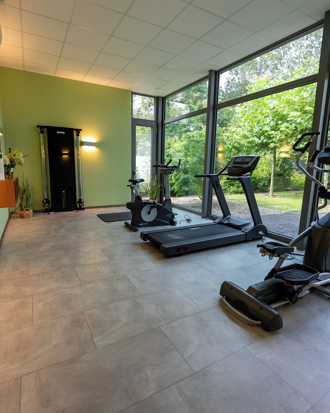 Une salle de sport équipée de tapis de course, d’un vélo d’appartement et d’un rameur.