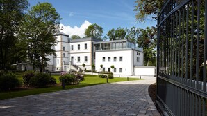 A modern building with a paved entrance and a metal fence. - Hotel Rittergut Störmede (Geseke)