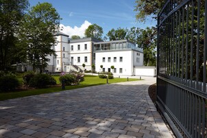 Um edifício moderno com entrada pavimentada e cerca de metal.