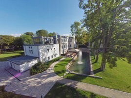 Um edifício moderno com um pátio, uma fonte e um gramado bem cuidado.