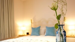 Un dormitorio con una cama, un florero con flores y dos lámparas de noche.