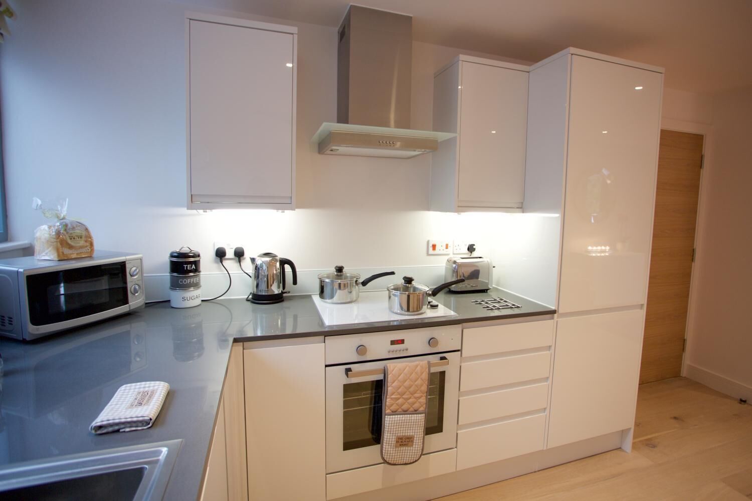 A modern kitchen with a microwave, kettle, toaster, and oven.