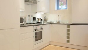 Una cocina moderna con armarios blancos, horno integrado, microondas y ventana con vistas al exterior.