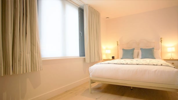 A bedroom with a bed, curtains, a window, and bedside lamps. - Citystay Living - Citygate (Cambridge)