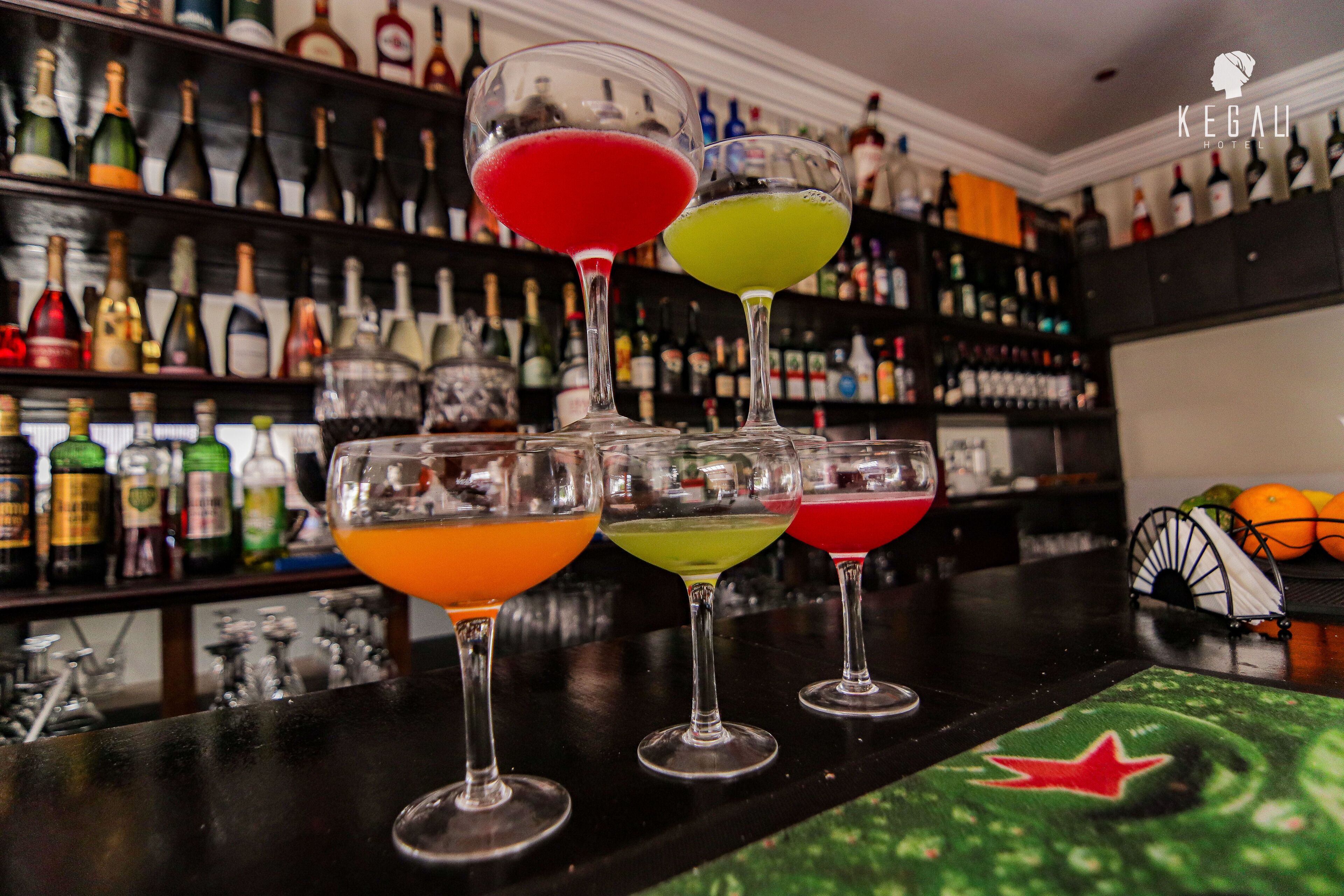 A bar with a variety of colorful cocktails and a backdrop of neatly arranged liquor bottles.