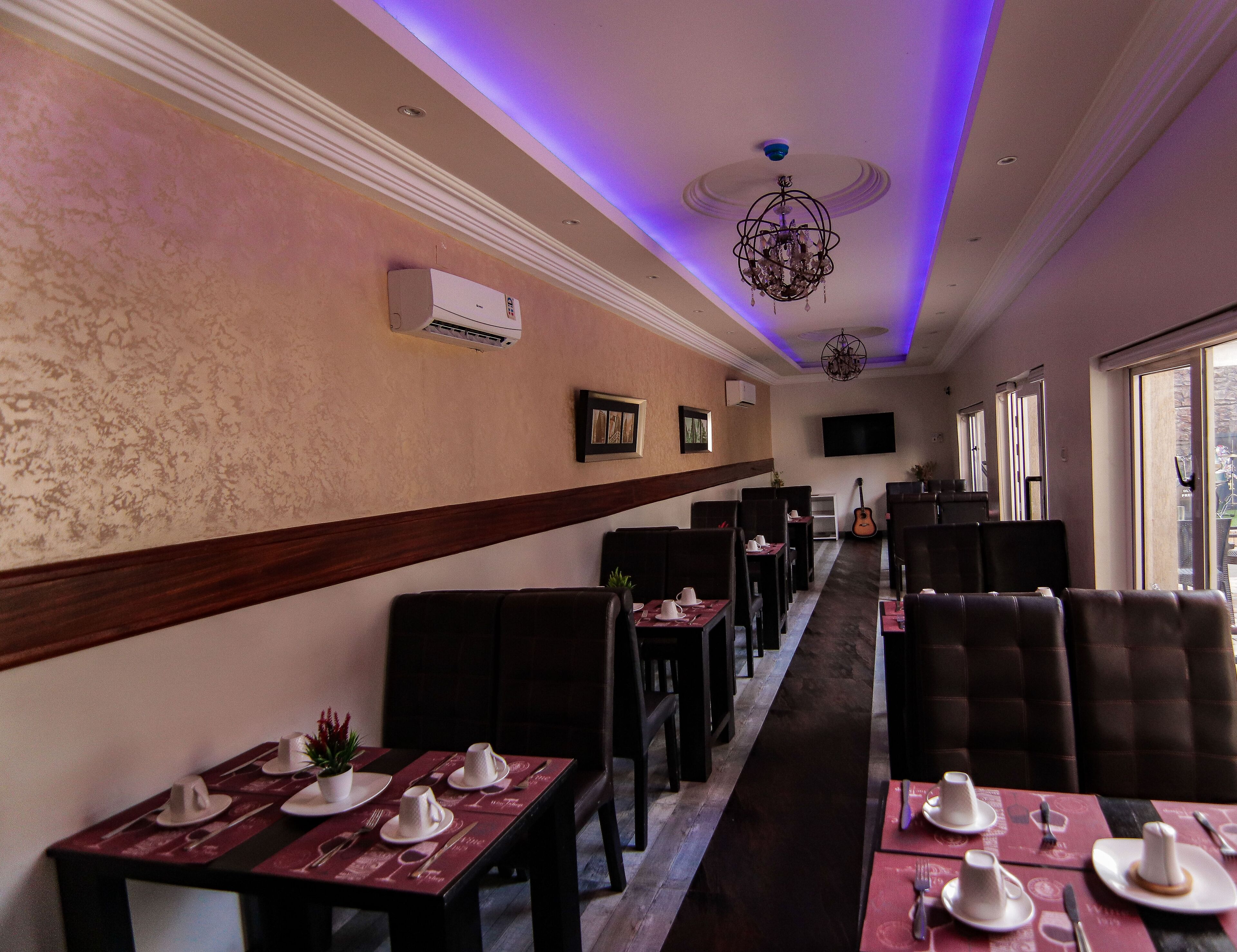 A restaurant with a long dining area, dark booths, and tables set with white tableware.