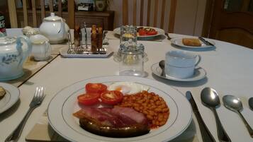 A dining table set with plates of food, cutlery, and a teapot.