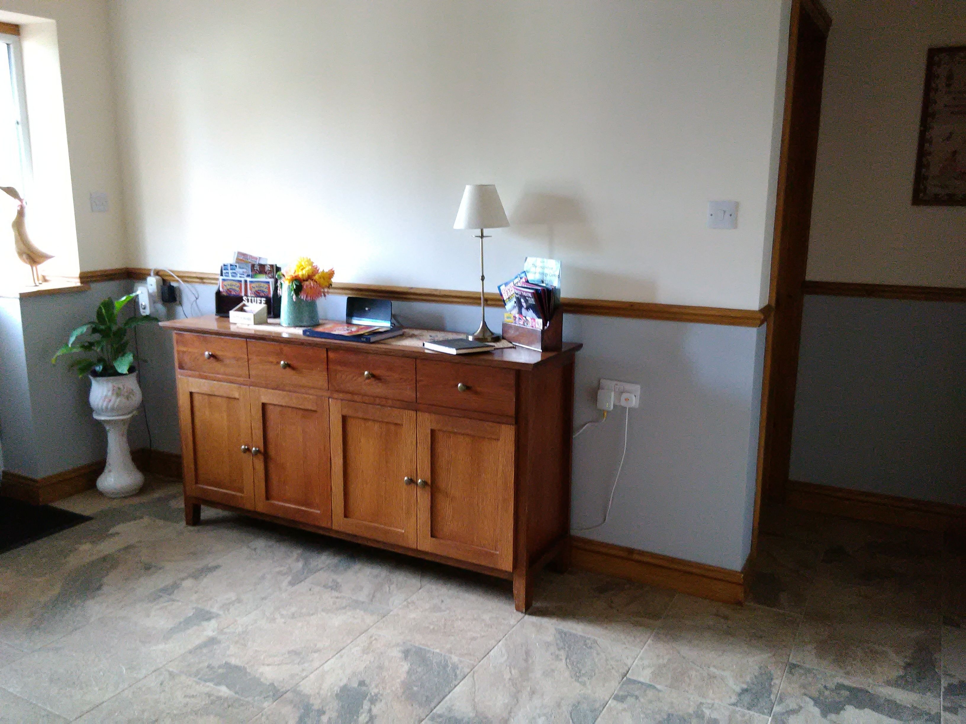 A wooden cabinet with drawers, a vase with flowers, and a lamp on top.