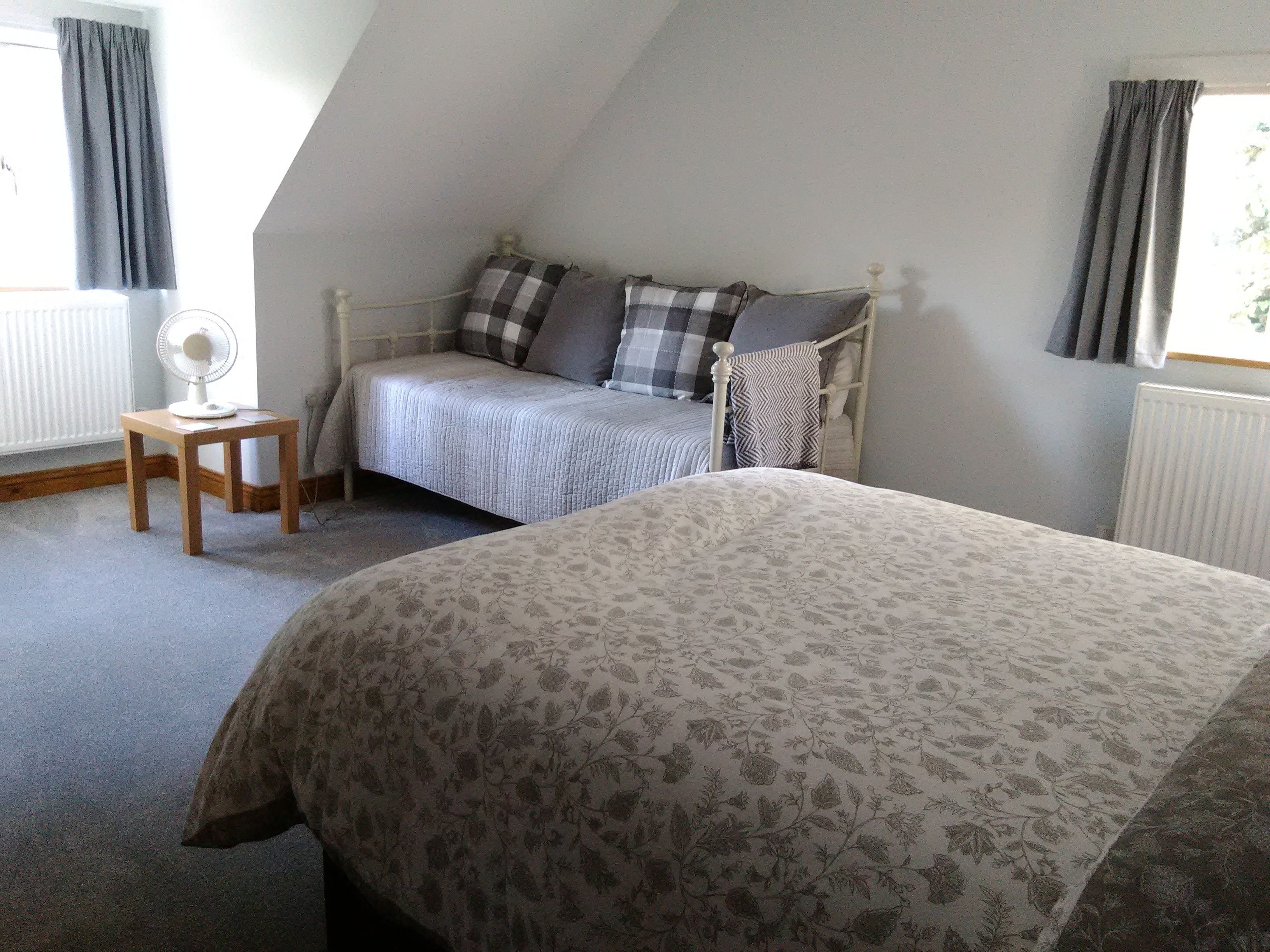A bedroom with a bed, a bedside table, a chair, and a window.