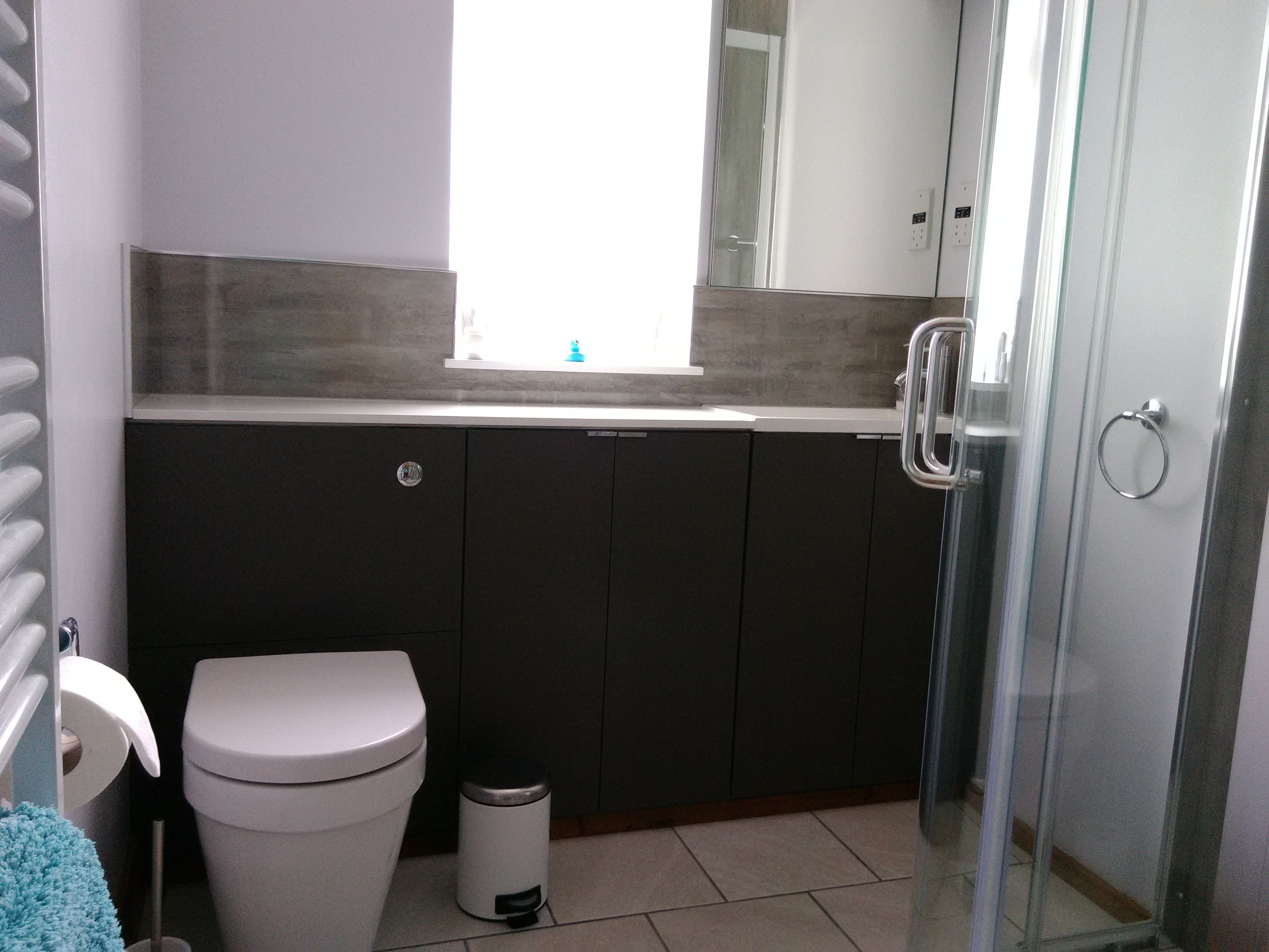 Ein Badezimmer mit Toilette, Mülleimer, Handtuch und Duschbereich.