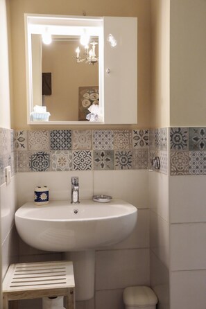 A bathroom with a white sink, a mirror, and a patterned tile backsplash. - Le Finestre Sul Borgo Rooms (Peschiera del Garda)