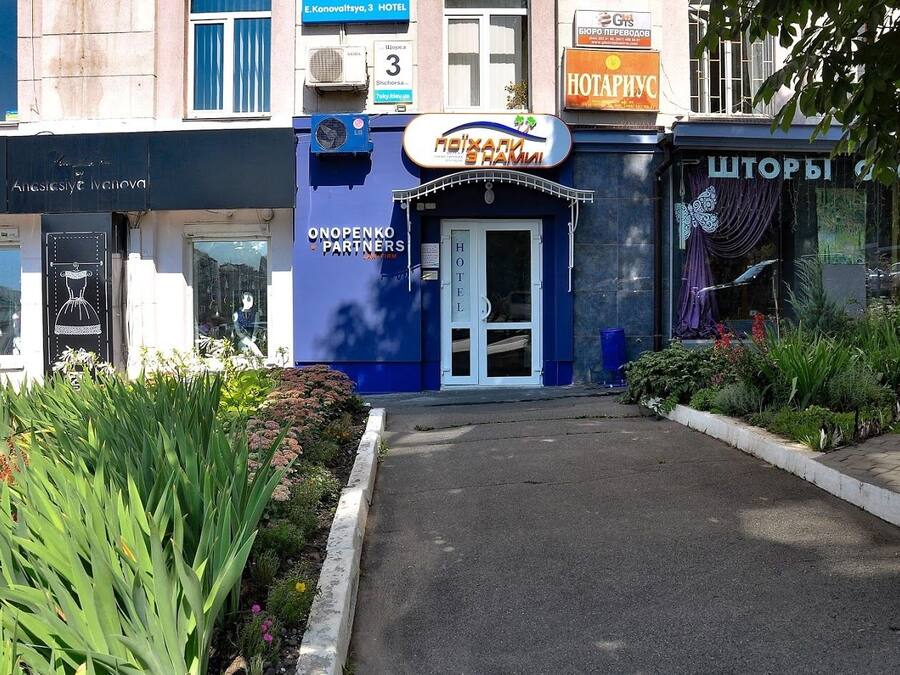 A hotel entrance with a blue facade, a sign for 'Onopenko Partners', and a visible entrance door.