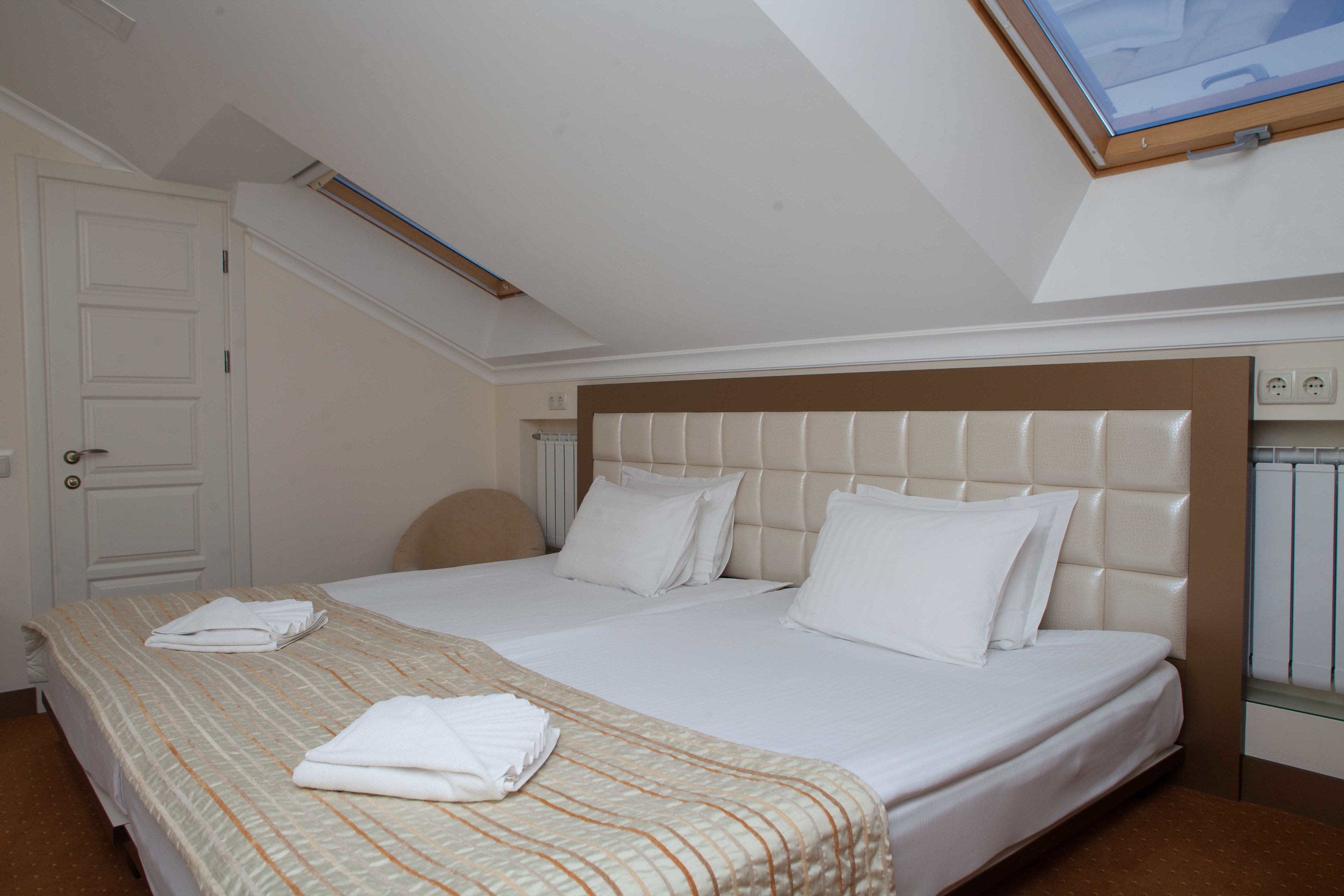 Una habitación de hotel con una cama grande, cabecera, ventana y puerta.