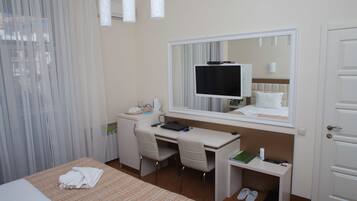 Ein Hotelzimmer mit Bett, Schreibtisch, Stuhl, Fernseher, Spiegel und Tür.