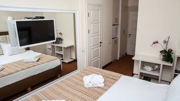 Quarto de hotel com cama, televisão, escrivaninha e guarda-roupa.