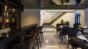 Un interior moderno con una zona de bar, comedor y una escalera que conduce a un nivel superior.