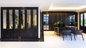 Un interior moderno con una puerta negra grande, una zona de bar con dos sillas y una vista al balcón a través de la puerta.