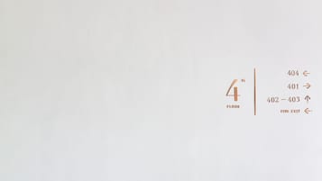 Un escalier avec une rampe en métal noir et un mur indiquant les numéros des étages et les directions.