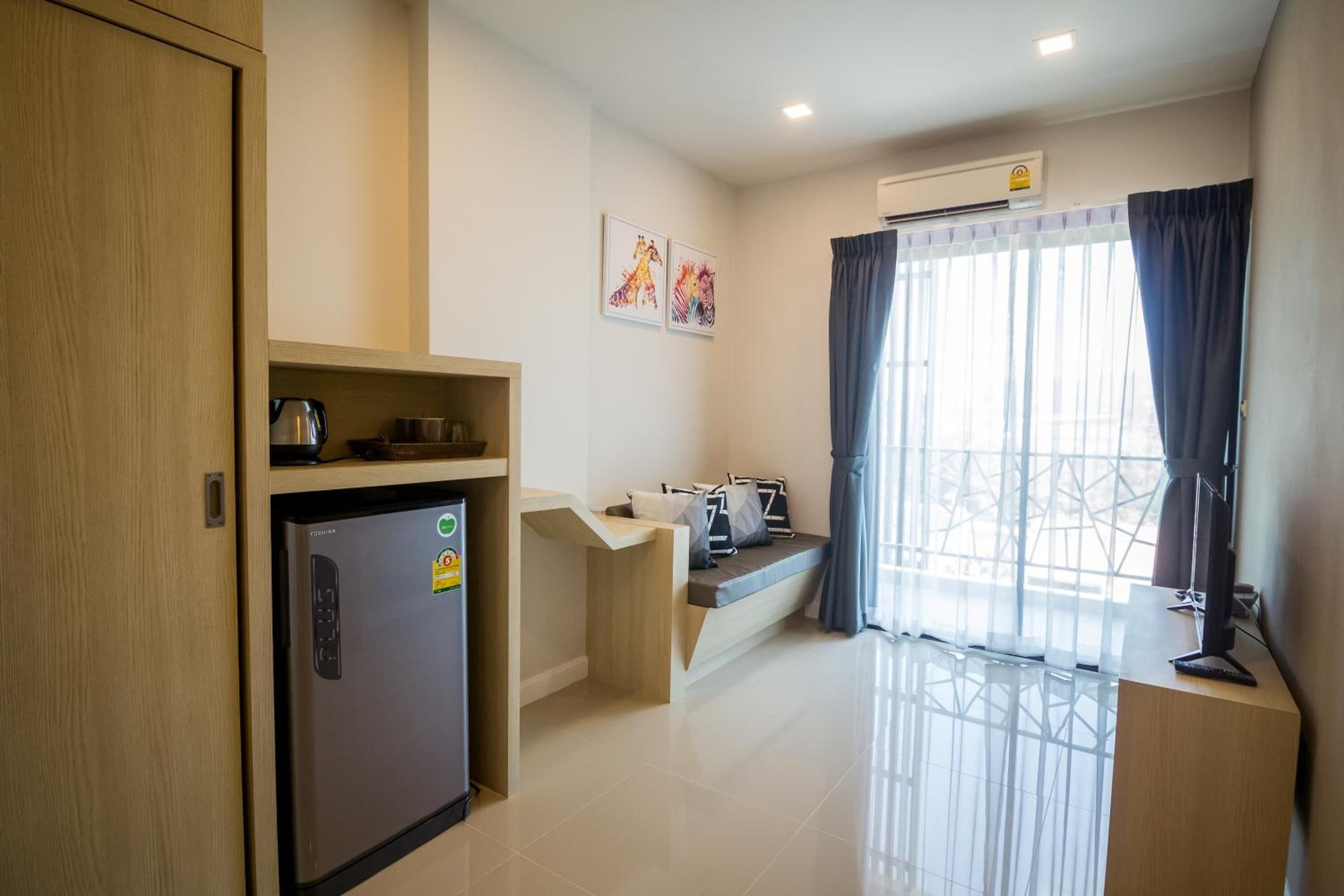 A compact living space with a kitchenette, a bed with a view, and a small seating area.