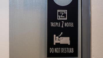 Une porte de chambre d’hôtel avec une pancarte « NE PAS DÉRANGER » et une autre indiquant « HÔTEL TRIPLE Z ».