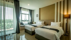Une chambre d’hôtel avec deux lits, une grande fenêtre avec des rideaux, un mur à motifs et un lampadaire.