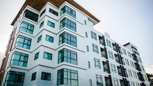 Un immeuble moderne à plusieurs étages, doté d’une façade blanche et de grandes fenêtres.