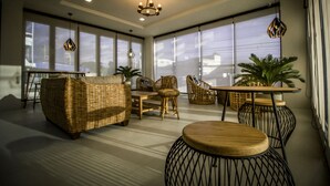 Un intérieur moderne avec des meubles en osier, une table ronde en bois et des lampes suspendues.