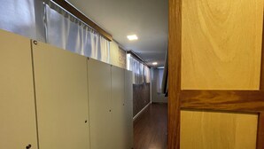 A hallway with lockers, wooden flooring, and a door on the right. - Eleganz Hostel & Suites (Gramado)