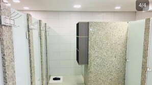 A public restroom with granite walls, a wooden bench, and a TV mounted on the wall. - Eleganz Hostel & Suites (Gramado)