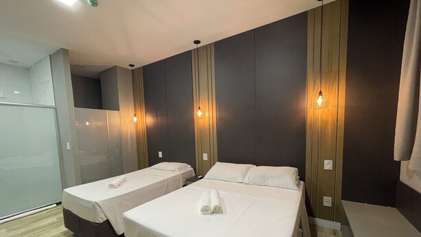 A hotel room with two beds, a wooden floor, and a modern design. - Eleganz Hostel & Suites (Gramado)