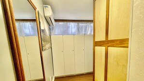 A room with wooden flooring, a white wardrobe, and a mirror. - Eleganz Hostel & Suites (Gramado)