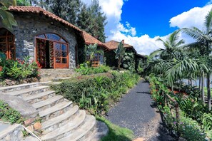 A stone house with a tiled roof, a stone staircase, and a garden path. - The Palm Beach Resort (Nyayumba)