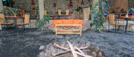 A rustic interior with a stone wall, wooden furniture, and a central seating area.