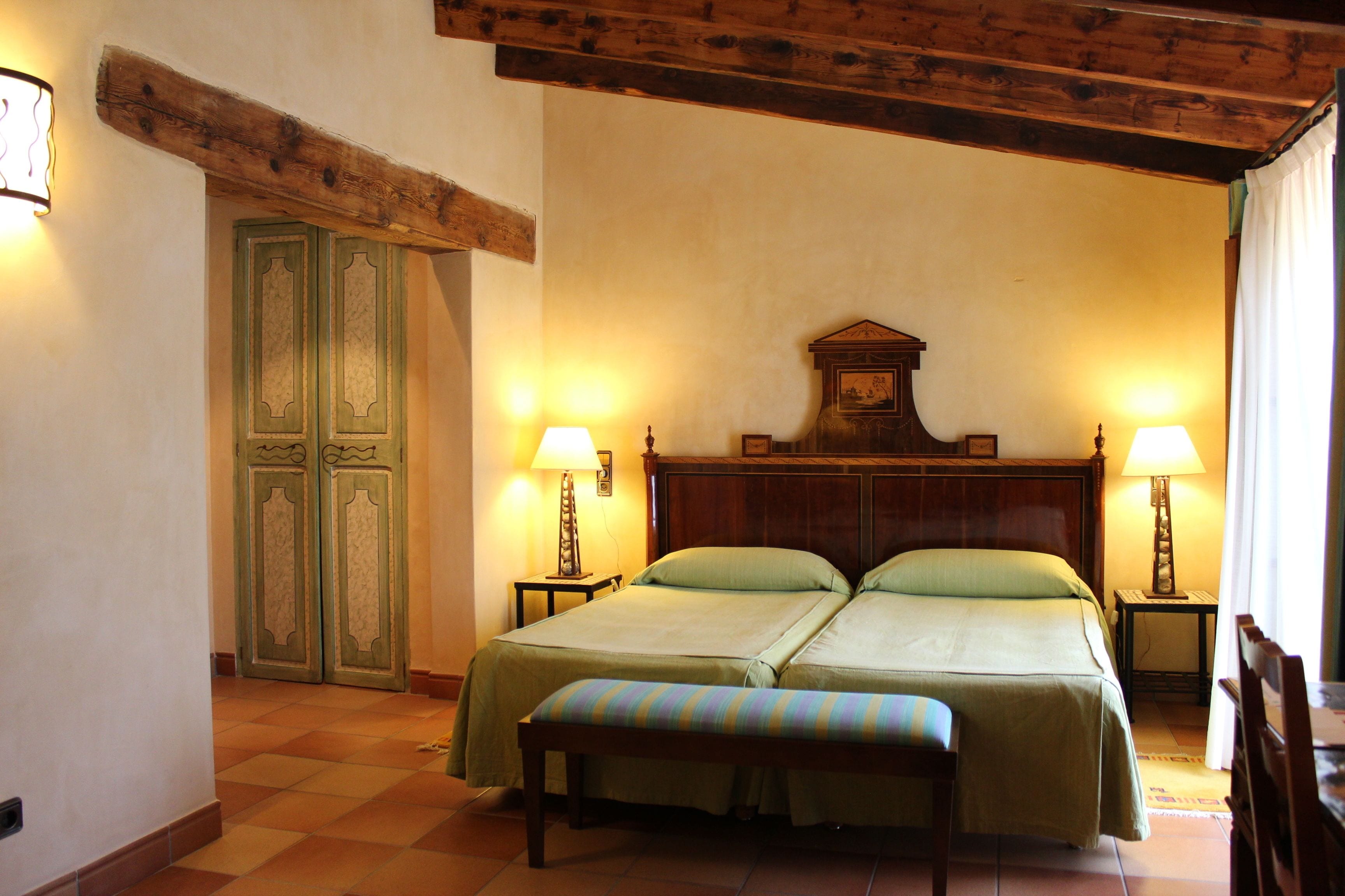 A double bed with two bedside tables, a bench, and a wooden headboard.