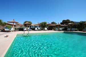 Una piscina al aire libre, sombrillas, tumbonas