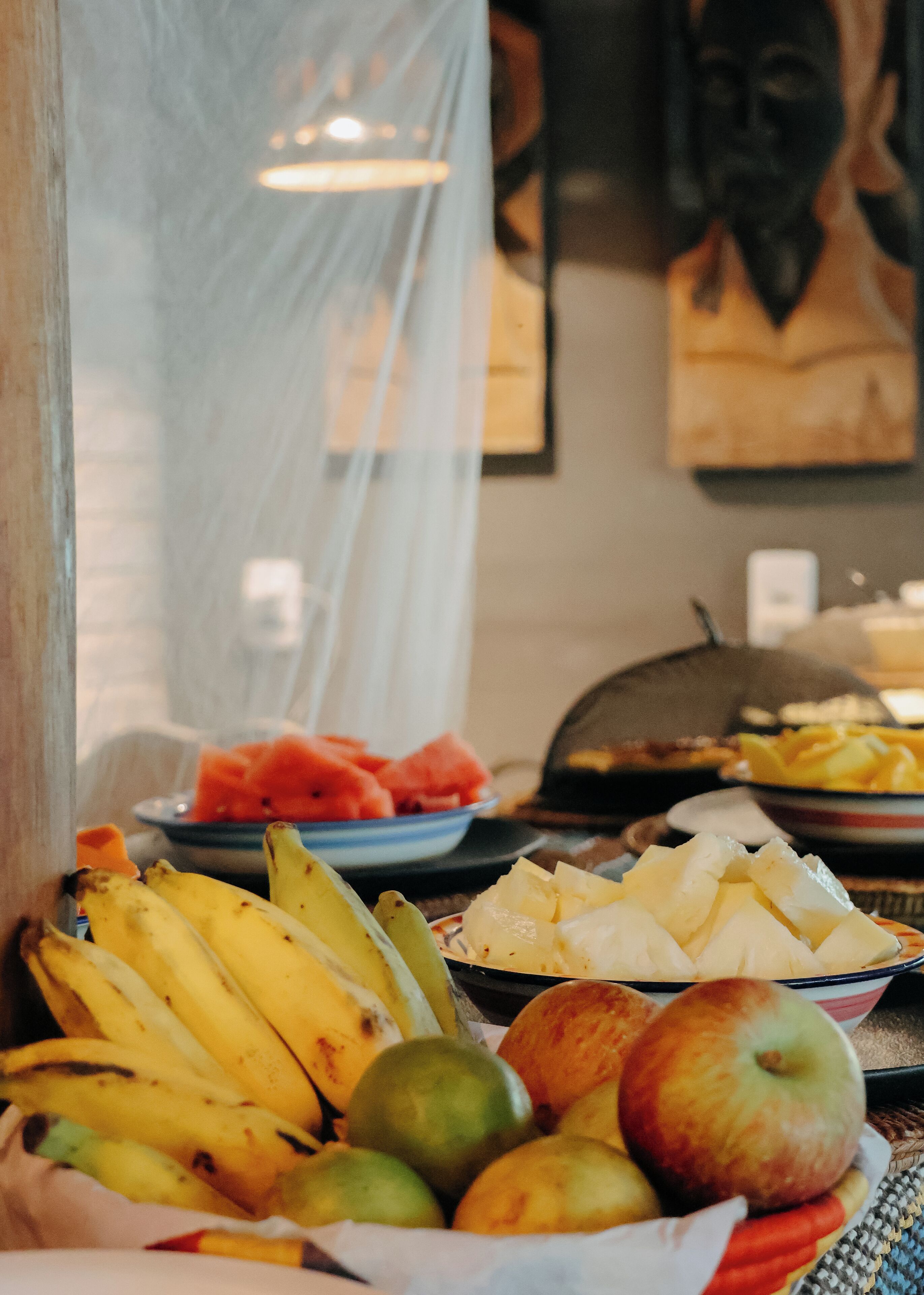 Una mesa con una variedad de frutas, como plátanos, manzanas y sandía.