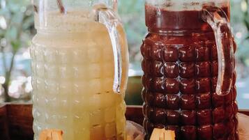 Two glass containers with straws, one filled with a light-colored beverage and the other with a dark beverage, placed on a wooden surface with labels.