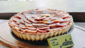 Ein Kuchen mit Apfelscheiben, auf einer Holzplatte serviert, neben der ein Schild steht.