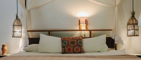 A bed with a canopy, two wall-mounted lamps, and a patterned pillow.