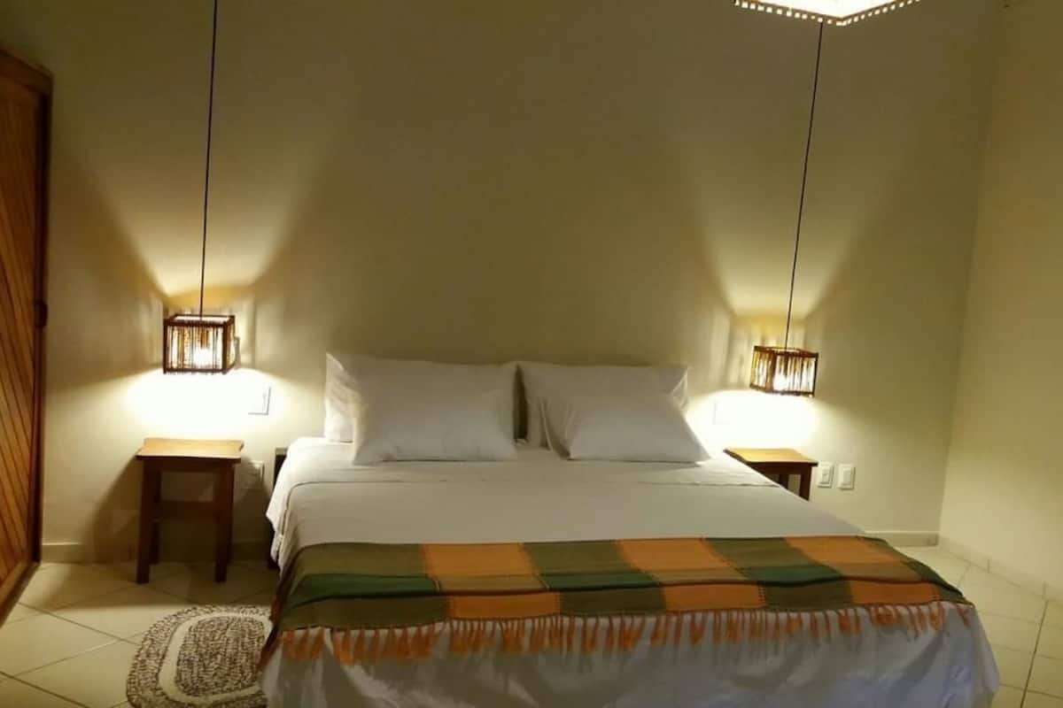 A bedroom with a bed, two bedside tables, and two wall-mounted lamps.