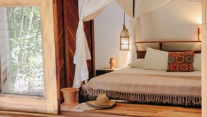 A bedroom with a bed, a nightstand, a vase, a hat, and a window with curtains.