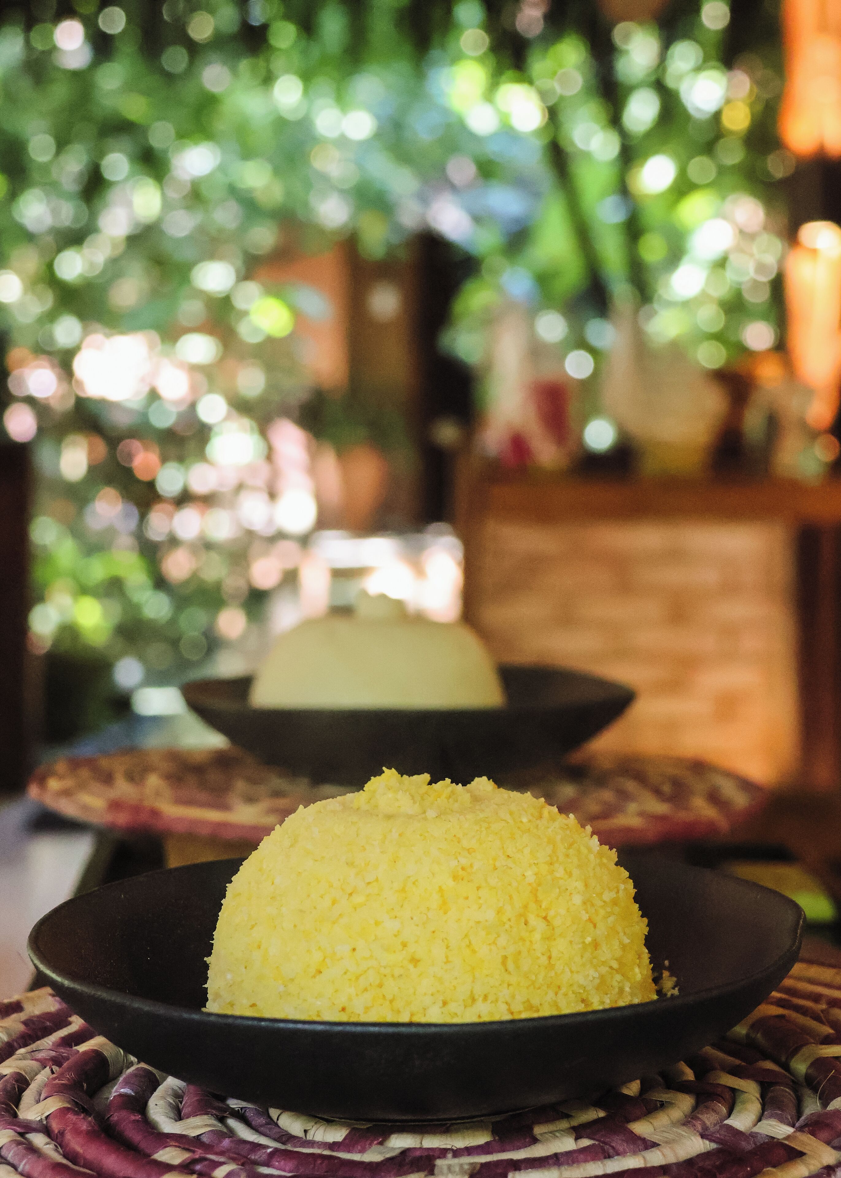 A bowl of yellow rice on a woven mat.