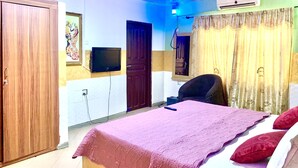 A bedroom with a bed, a chair, a television, and a wardrobe. - Sundowner Lodge (Tamale)