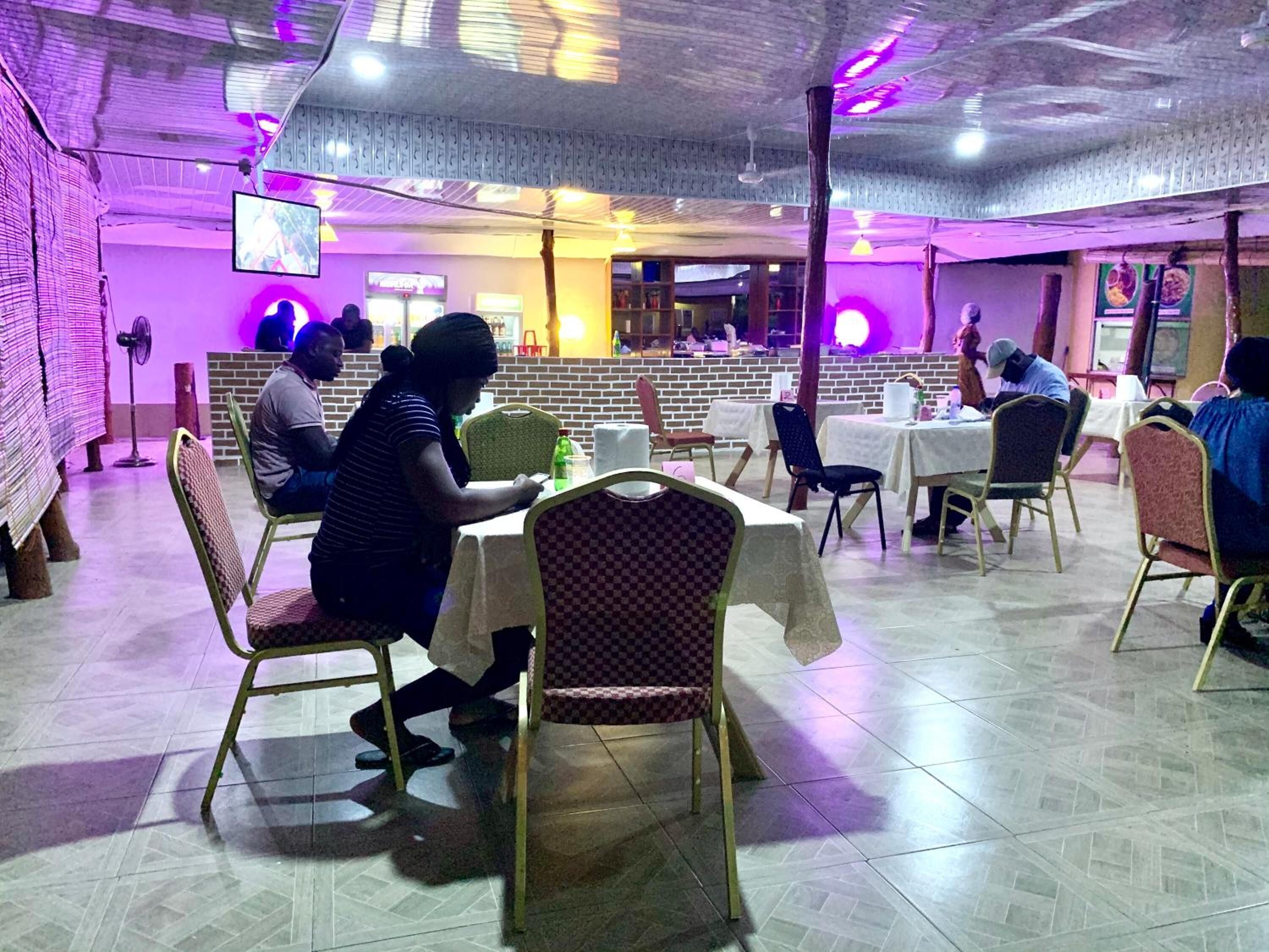 Un restaurant doté de nombreuses tables et chaises, d’un mur en briques et d’un plafond avec des poutres apparentes.