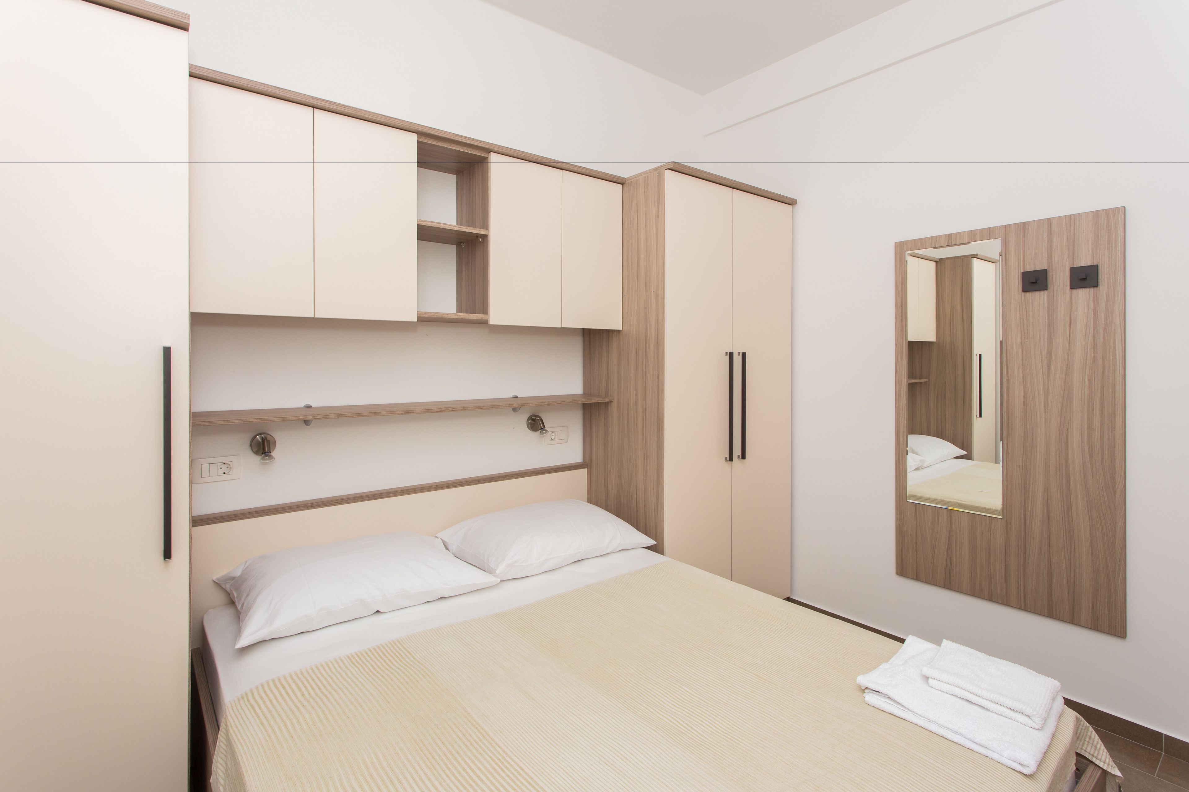A bedroom with a bed, a wardrobe, and a mirror.