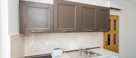 A modern kitchen with brown cabinets, a built-in stove, a sink, and a toaster.