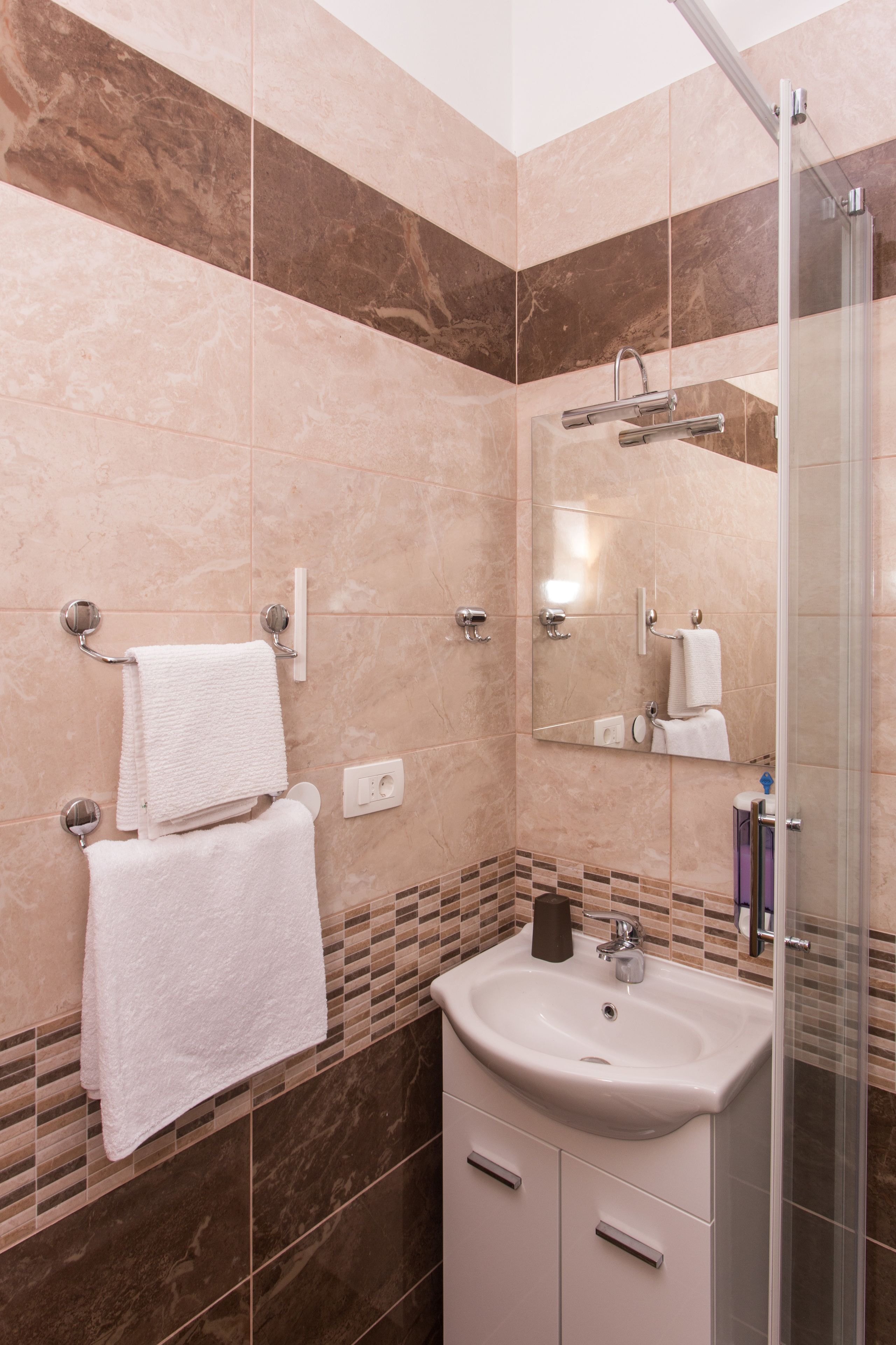 A bathroom with a sink, mirror, towel rack, and shower.