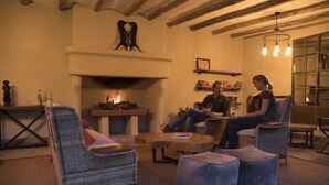 A cozy living room with wicker furniture, a fireplace, and a hanging light fixture. - Arusha Villa (Arusha)