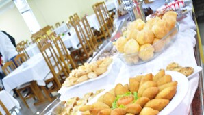 Een buffettafel met diverse etenswaren, zoals pizza, belegde broodjes en broodbollen.