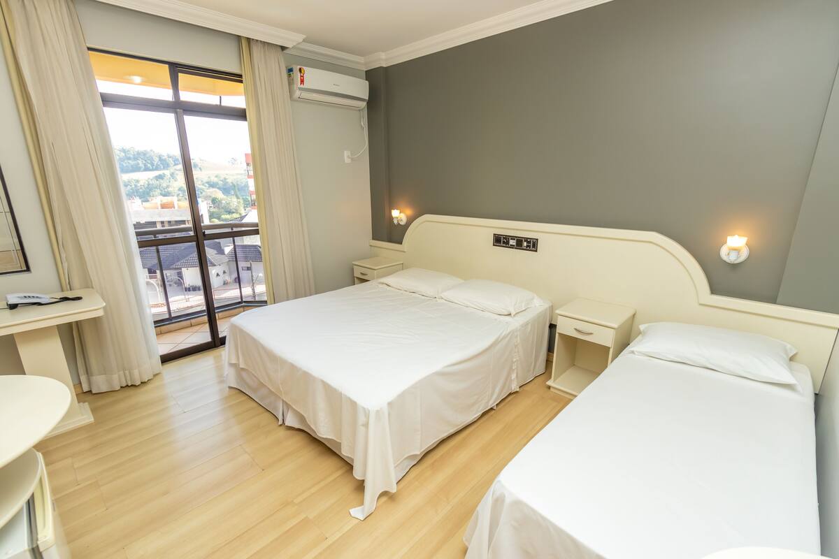 Ein Hotelzimmer mit zwei Betten, einem Schreibtisch und einem Fenster mit Vorhängen.